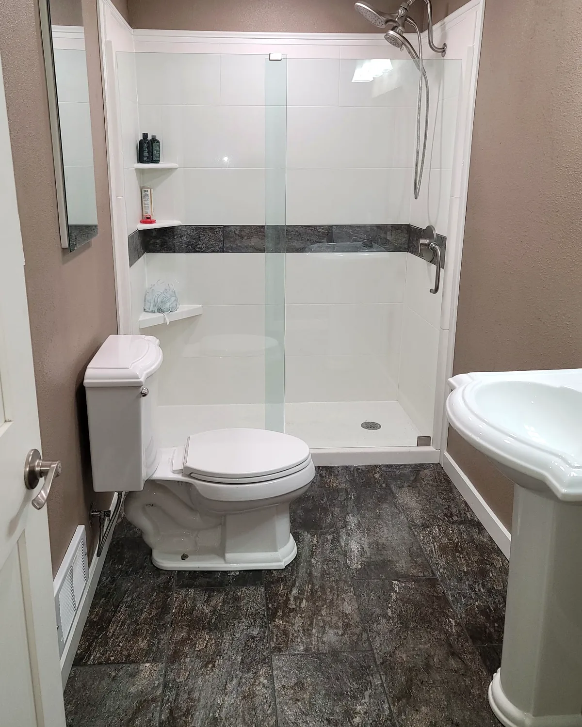 After: the same bathroom with a walk-in shower, glass panel, and new tile floor