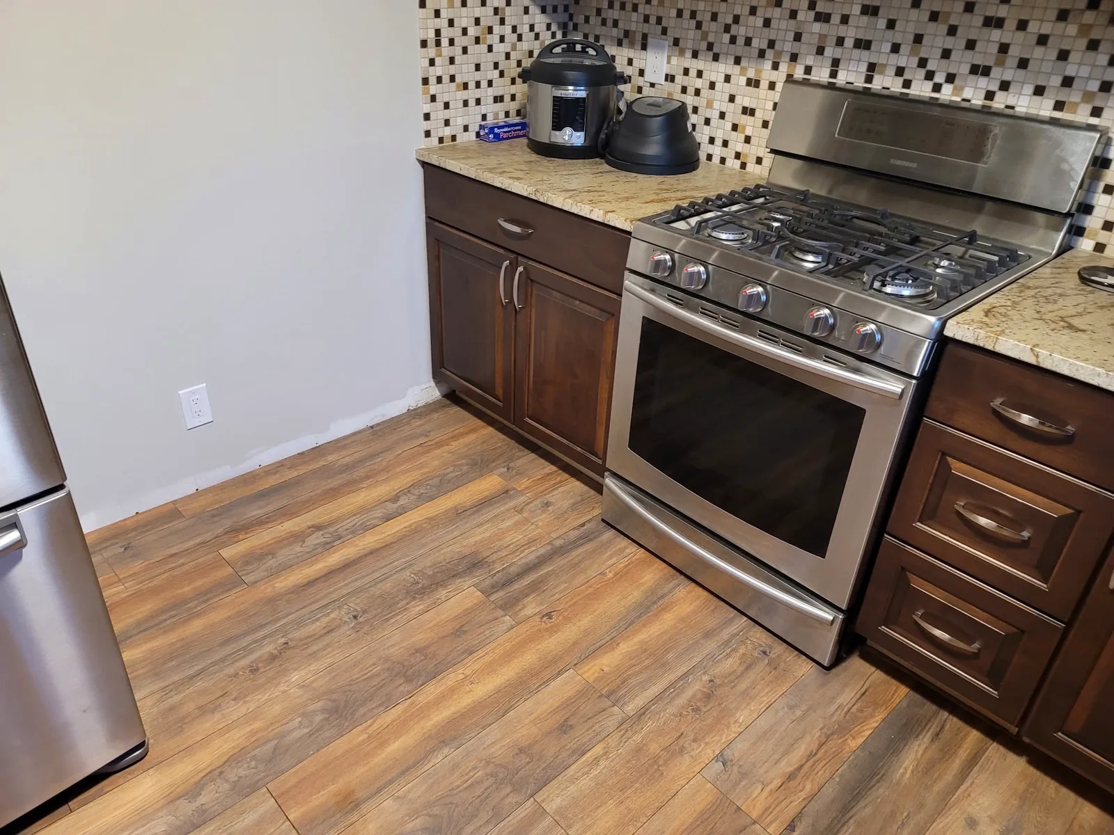 Kitchen with new wood-look flooring running beneath the range and cabinets