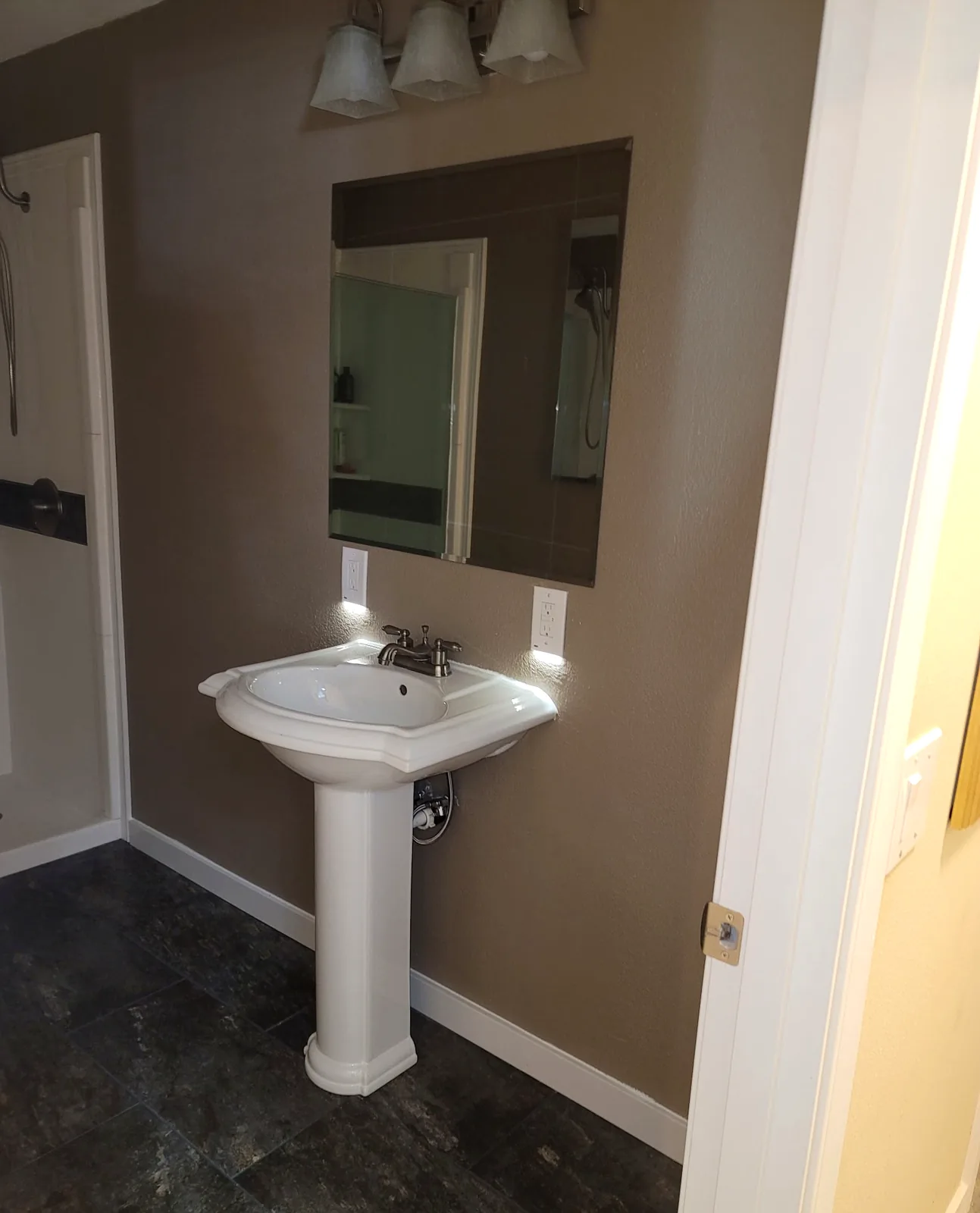 Bathroom with pedestal sink, frameless mirror, and new flooring